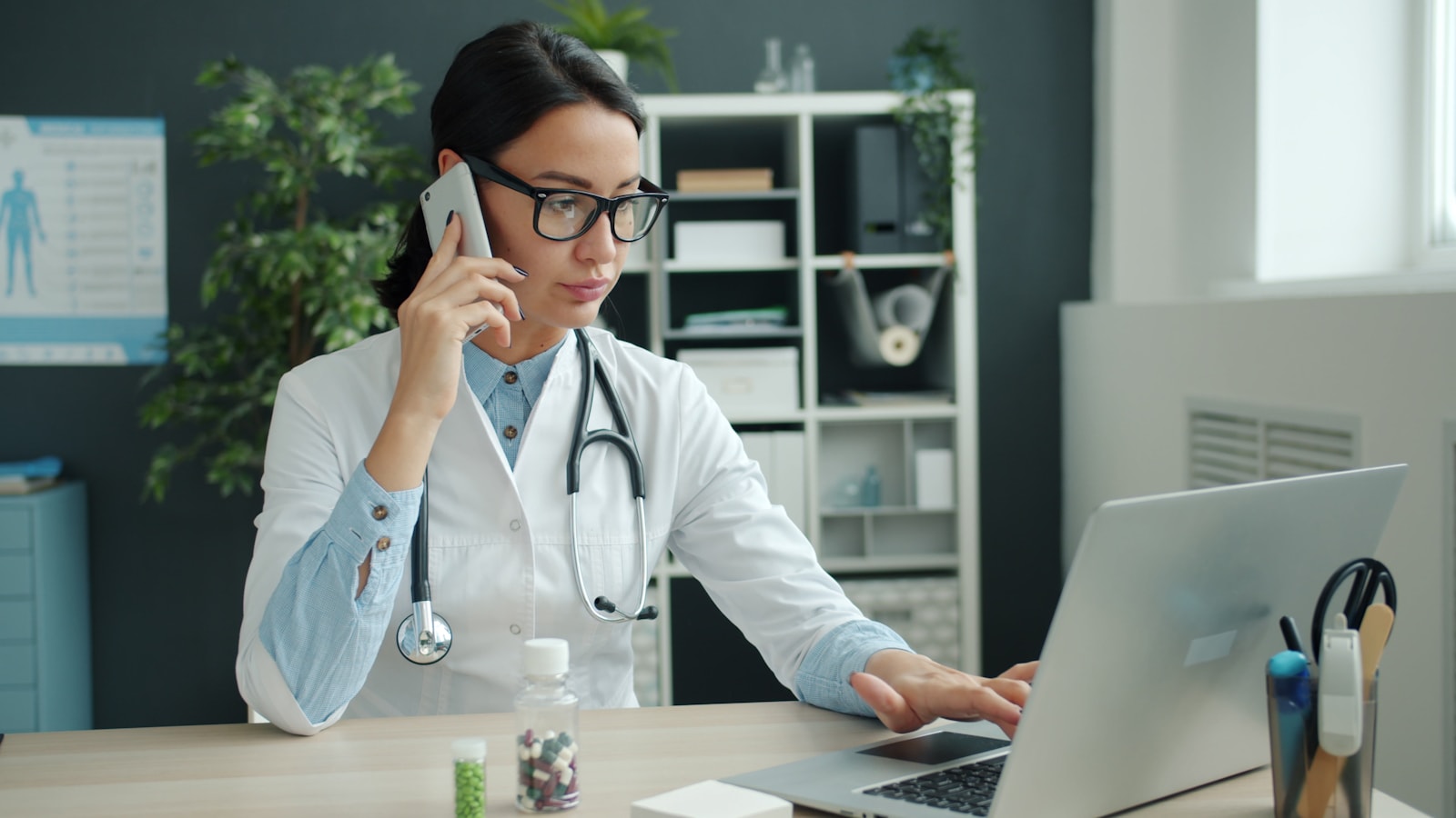 Médica sorridente analisando a agenda cheia de pacientes no notebook em consultório